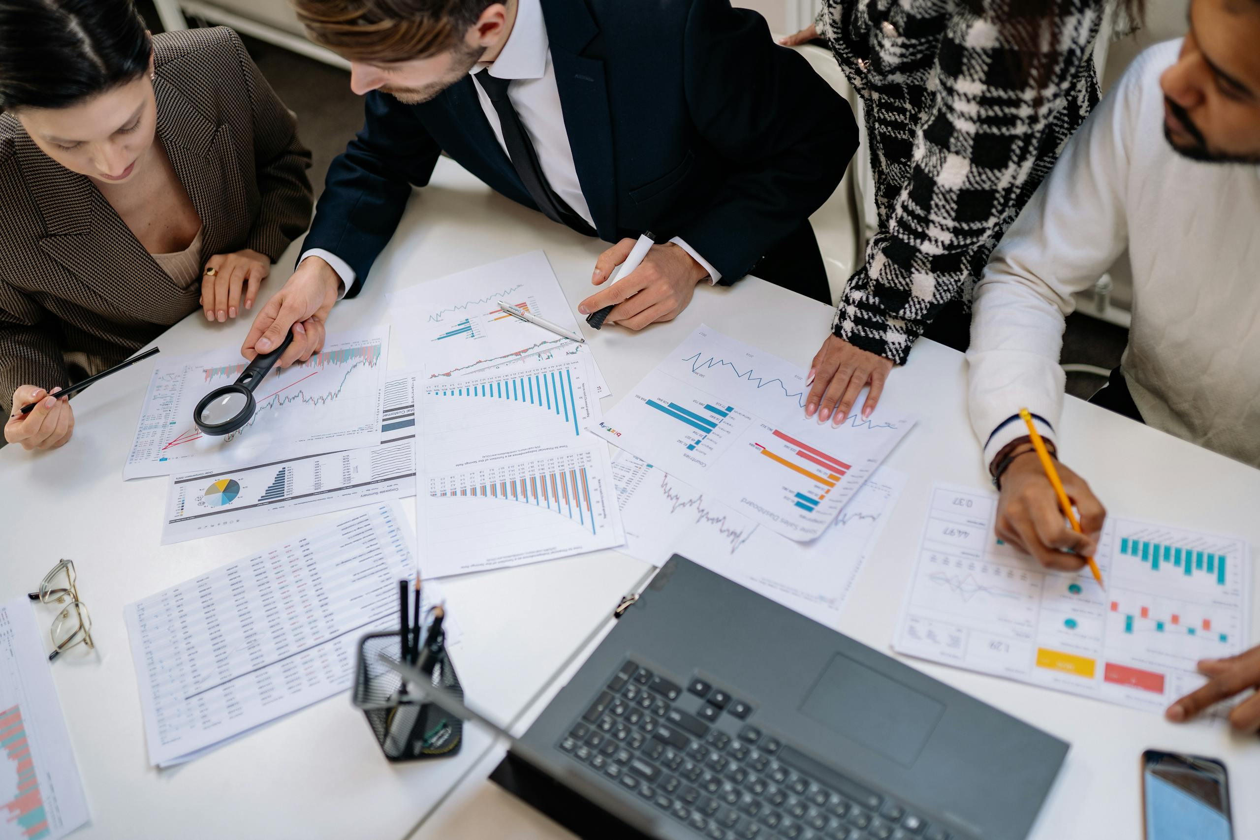A group of professionals reviewing financial charts in an office meeting setting.