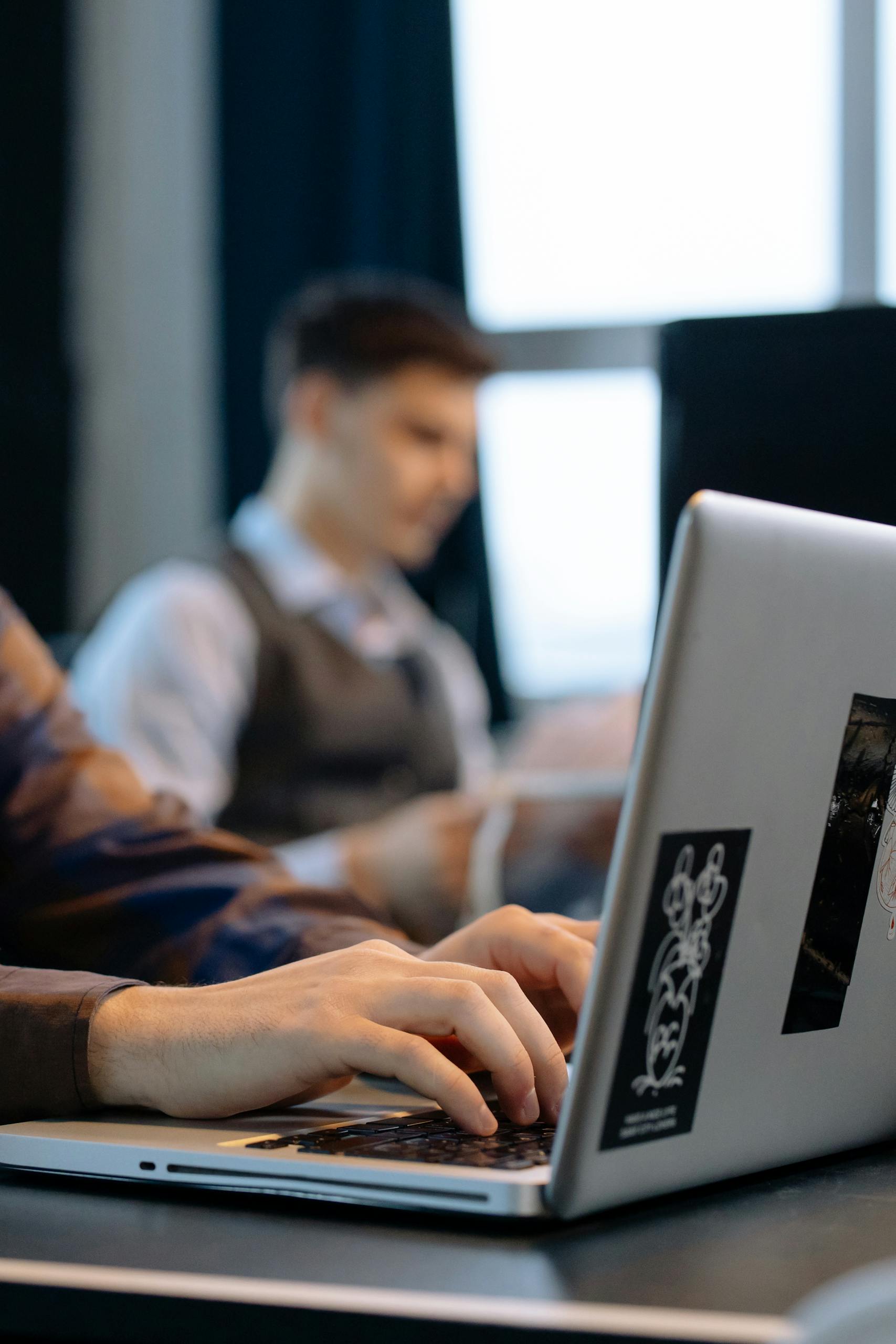 A professional working on a laptop in a contemporary office setting, focused on technology and productivity.