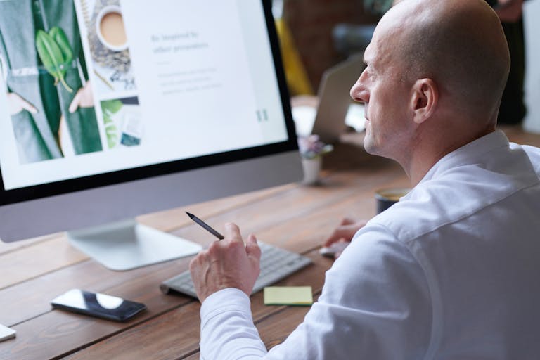 Bald man concentrates on work using computer in modern office. Sleek design and digital tools enhance productivity.