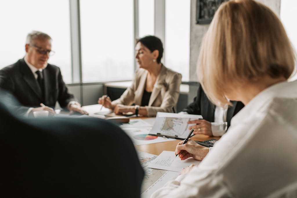 Colleagues discussing documents in a corporate office meeting.