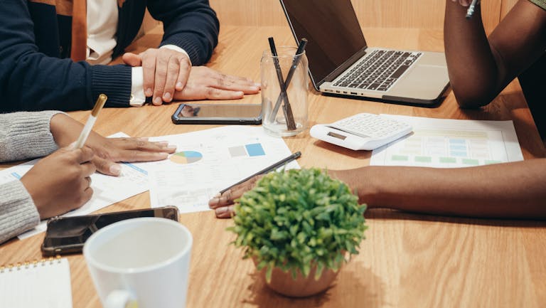 Diverse team collaborates on a business project with charts and laptops in a modern office setting.