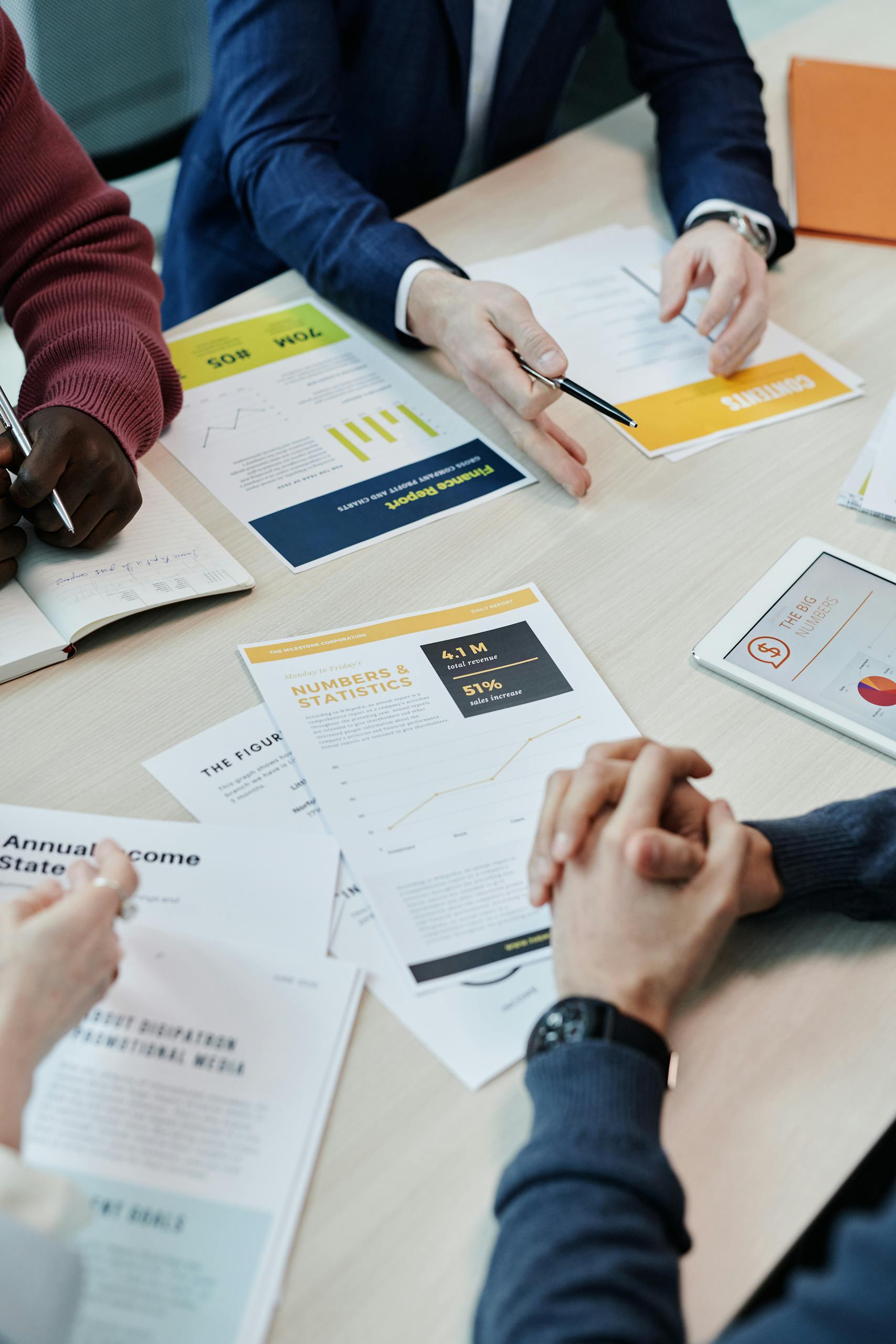 Team members discuss data reports and statistics in a collaborative setting around a table.